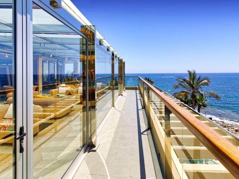Balcon moderne avec vue sur la mer et mobilier confortable sous le soleil.