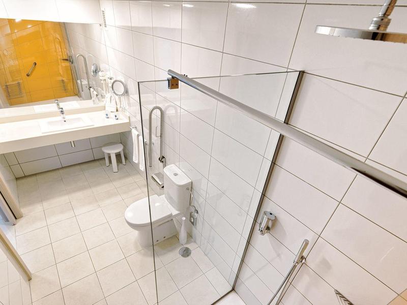 Salle de bain moderne avec douche à paroi vitrée, toilettes et lavabo sous miroir.