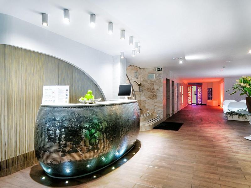 Réception d'hôtel moderne avec comptoir incurvé, éclairage doux et plantes décoratives.