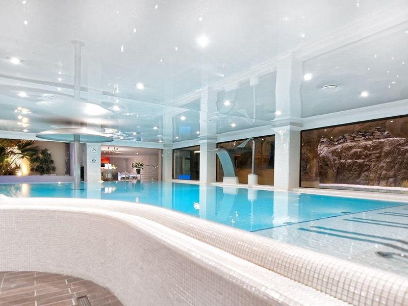 Piscine intérieure moderne avec éclairage doux et mur d'eau décoratif dans un hôtel.