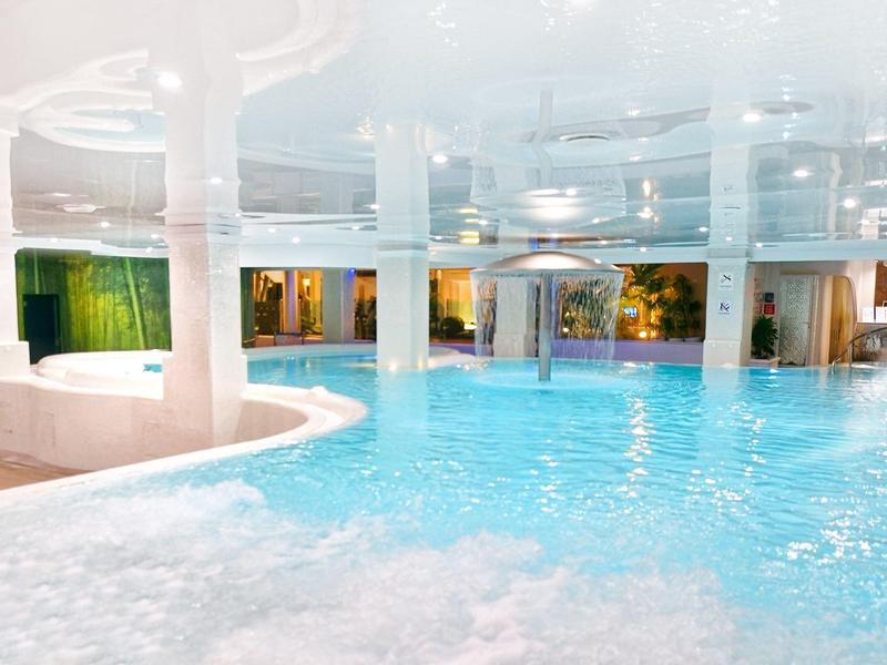Piscine intérieure avec eau turquoise et colonne blanche, ambiance lumineuse et relaxante.