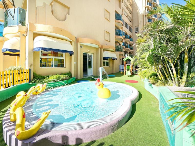 Piscine extérieure ludique avec canards jaunes et décor clair dans un jardin d'hôtel.