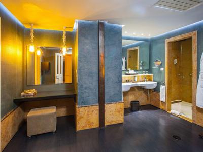 Geräumiges Hotelbad mit blauen Wänden, großer Badewanne, Waschbecken und Hocker.