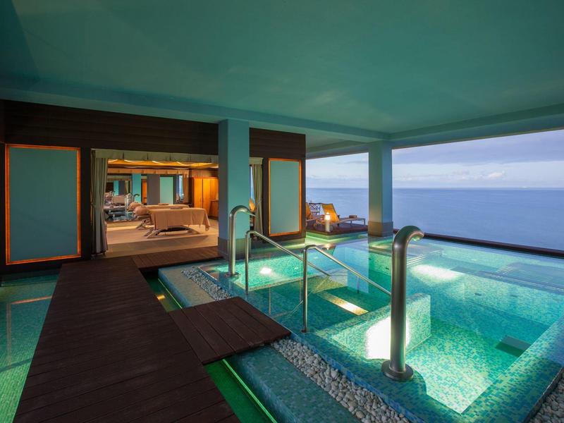 Piscina de hotel moderna con borde de vidrio y vista al mar en un espacio abierto.
