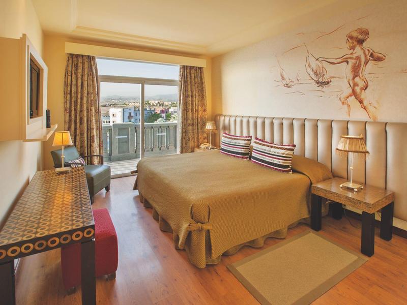 Habitación de hotel acogedora con cama grande, alfombra, escritorio y ventana con vista al exterior.