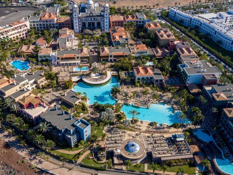 Vista aérea de un gran resort con varias piscinas, edificios y áreas verdes.