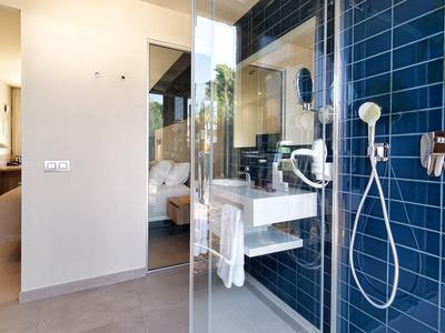 Modernes Badezimmer mit blauen Fliesen, Glasdusche, weißem Waschbecken und großem Spiegel.