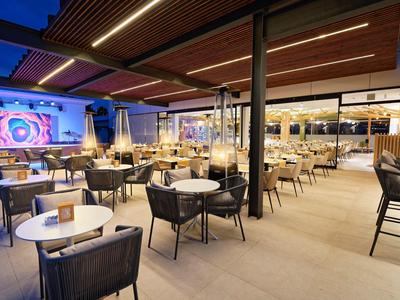 Moderner, heller Restaurantbereich mit Holzdecken, gemischten Sitzgruppen und großem Fensterfrontbereich.