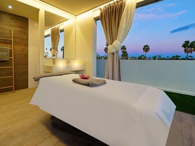 Moderner Wellnessraum mit Massageliege, offenem Balkon, warmem Holz und sanfter Beleuchtung.