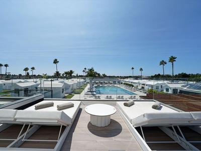 Área de piscina moderna con tumbonas y vistas al mar en un día soleado.