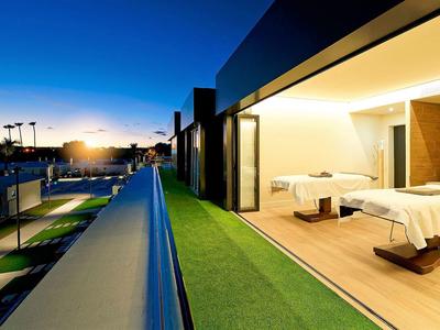 Moderner Balkon mit Liegestühlen und Graselementen bei Sonnenuntergang.