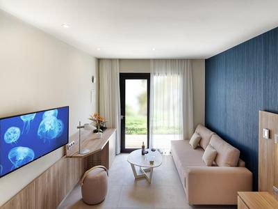 Modernes Wohnzimmer mit blauer Wand, grauem Sofa, Holzmöbeln und TV mit Quallen-Motiv.