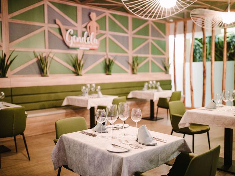 Gemütliches Restaurant mit grünen Stühlen, weißen Tischtüchern und modernem Wanddekor.