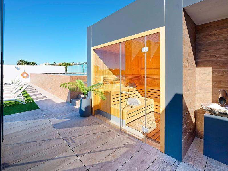 Moderner Außenbereich mit Holzboden, großen Glasfenstern und einem kleinen Outdoor-Waschbecken.