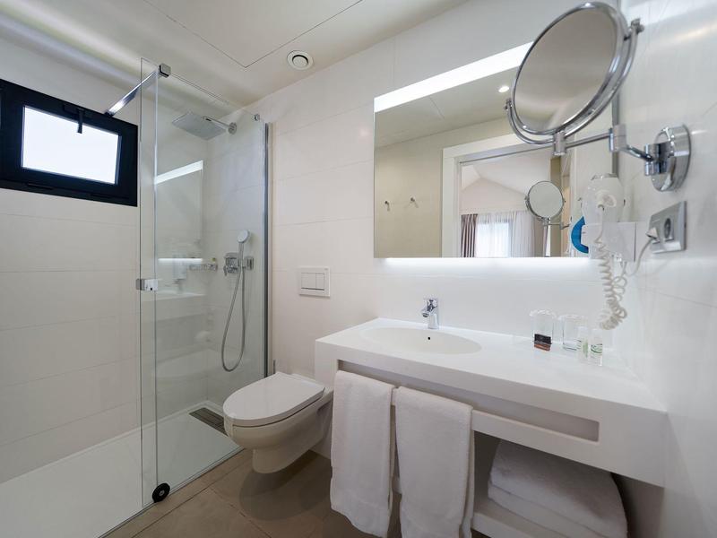 Modernes Badezimmer mit Glasdusche, weißem Waschtisch, Wandspiegel und hängendem Kosmetikspiegel.