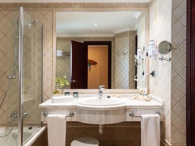 Helles Badezimmer mit Glasdusche, großem Spiegel, Waschbecken und weißen Handtüchern.