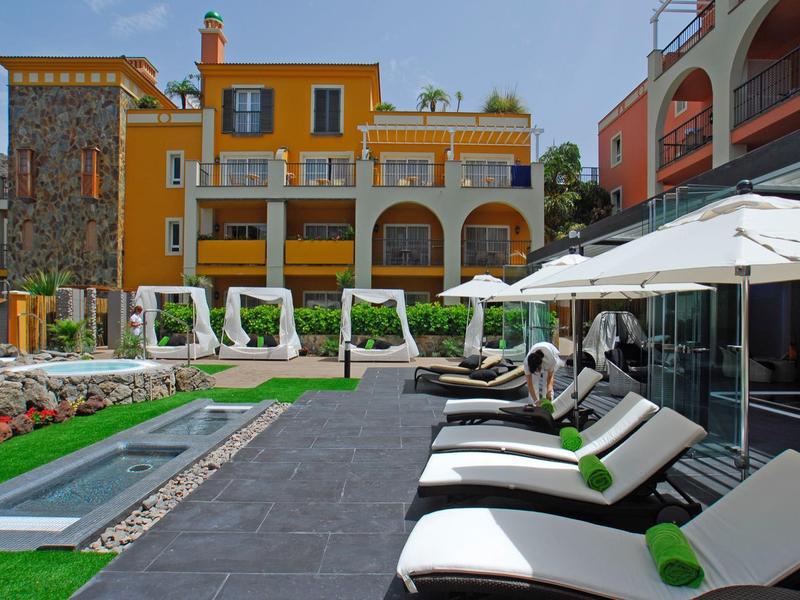 Outdoor pool area with lounge chairs and yellow building in the background