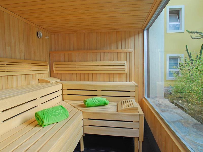 Bright sauna with wooden benches, green towels, and window view to nature.