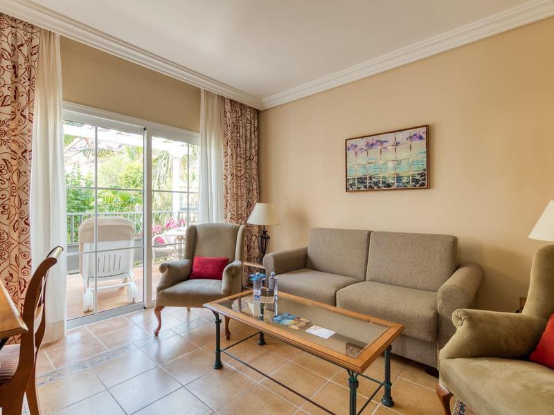 Cozy hotel room with sofa, armchairs, coffee table and balcony doors with curtains.