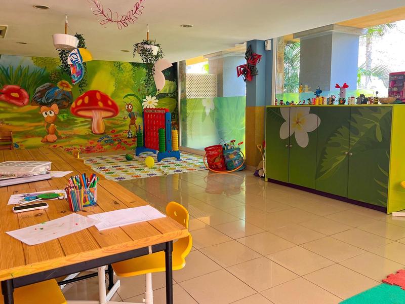 Bright kids' playroom with colorful furniture, toys, and a drawing table by a window.