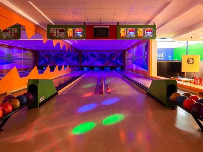 Colorful bowling alley with illuminated lanes and ball racks in a lively ambience.