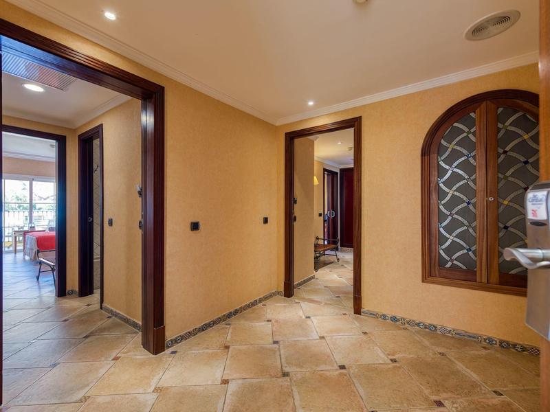 Hotel room hallway with beige tiled floor, light walls, wooden door frames, and a glass door