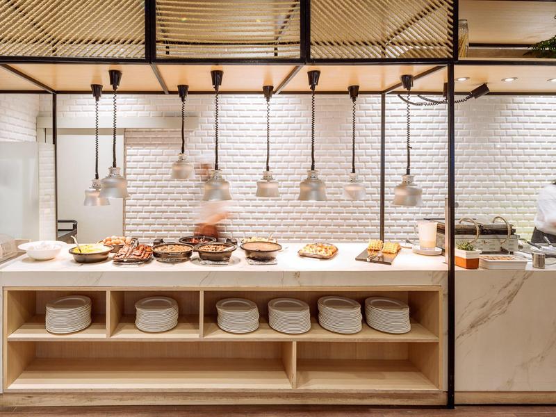 Bufet s různými pokrmy a naskládanými talíři v moderní restauraci.