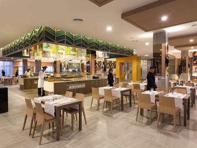 Restaurante moderno de hotel con mesas preparadas y área de buffet al fondo.