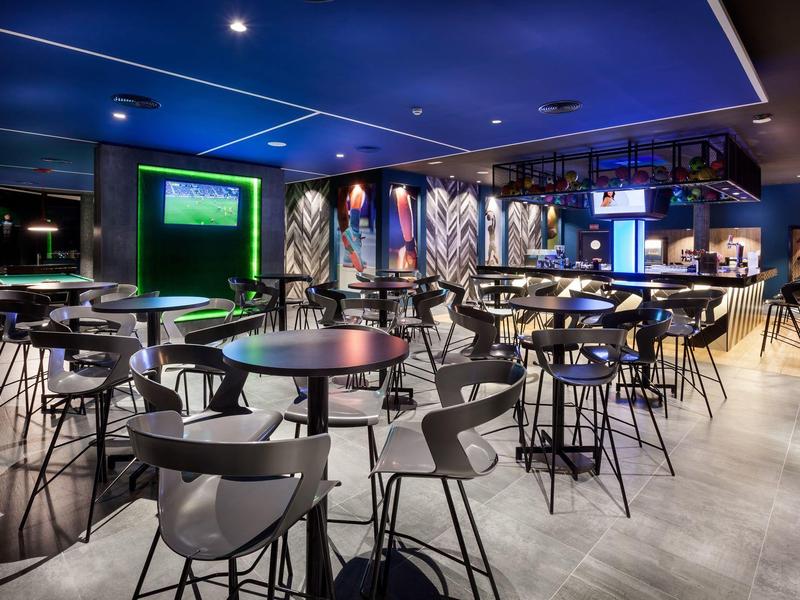 Área de bar moderna con mesas redondas y sillas en un ambiente elegante.