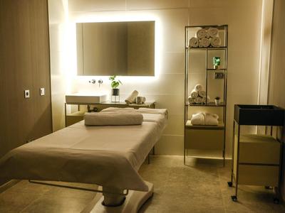 Przytulny pokój spa z stołem do masażu, podświetlanym lustrem i starannie ułożonymi ręcznikami