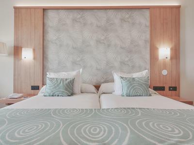 Nowoczesny pokój hotelowy z dużym łóżkiem, wzorzystymi poduszkami i drewnianymi ścianami.