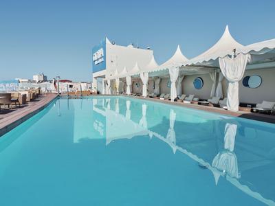 Basen na świeżym powietrzu z białymi kabinami i czystym niebieskim niebem w ośrodku.