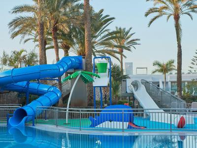 Park wodny z niebieskimi zjeżdżalniami i palmami obok basenu.