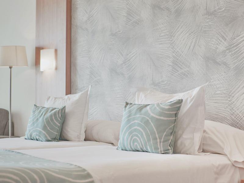 Nowoczesny pokój hotelowy z łóżkiem, poduszkami i miękkim oświetleniem.