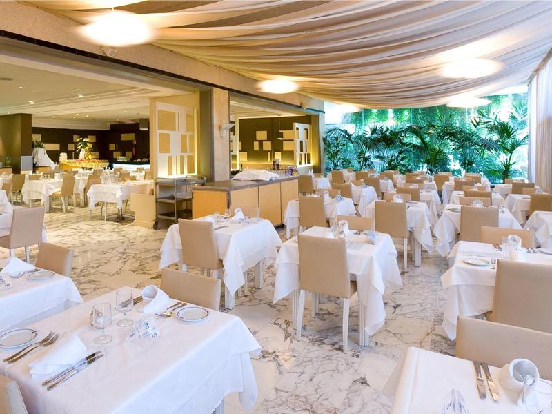 Elegancka restauracja na świeżym powietrzu z białymi obrusami i wygodnymi krzesłami pod markizą.