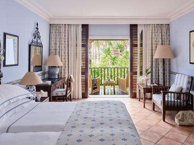 Hell eingerichtetes Schlafzimmer mit Doppelbett, Holzmöbeln und Balkon mit Blick ins Grüne.