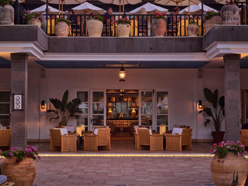 Gemütliche Außenterrasse mit Holztischen, Stühlen und Sonnenschirmen in einem eleganten Restaurant.