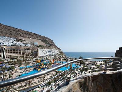 View of a resort with pools and sea on a sunny day.
