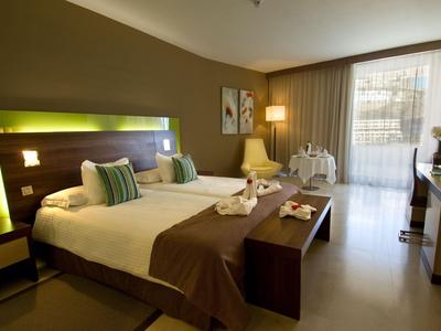 Modern hotel room with double bed, seating area, and balcony overlooking the outdoors.