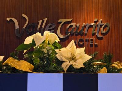 Hotel name Valle Taurito on brown wood with festive decoration and white flowers.