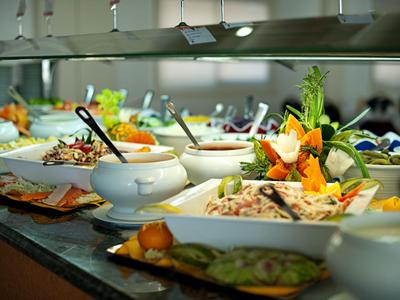 Buffet with various fresh salads and dressings in a hotel kitchen.