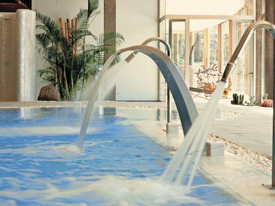 Indoor pool with multiple water jets and wooden decor in a hotel.