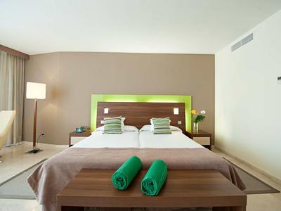 Moderne hotelkamer met een tweepersoonsbed, groene accenten en gezellige verlichting.