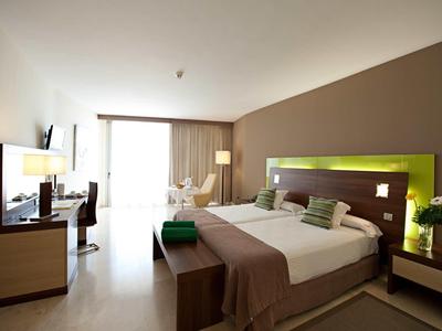 Modern hotelkamer met groot bed, bureau, tv en rustgevende kleuren.