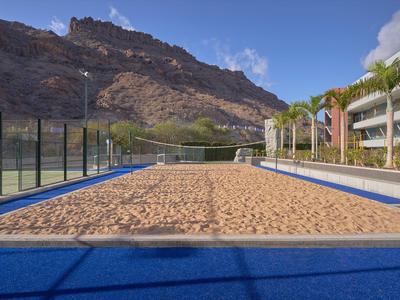 Beach volleyball sand court with mountain backdrop and hotel buildings