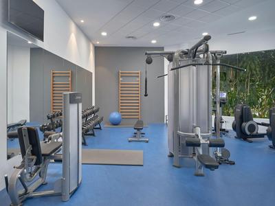 Modern gym with exercise equipment and blue flooring.