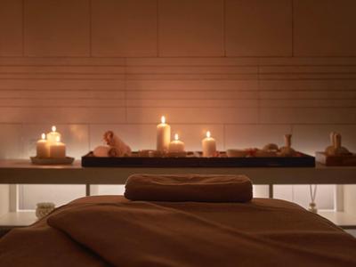 Sala de masajes acogedora con velas encendidas y luz cálida para relajación en hotel.