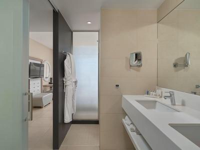 Baño moderno con lavabo, espejo grande y vista al dormitorio.