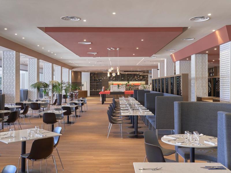 Restaurante moderno de hotel con mesas elegantes, sillas y puestos preparados en un ambiente luminoso.