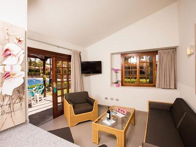 Cozy seating area with sofa, armchair, table, and pool view through French doors